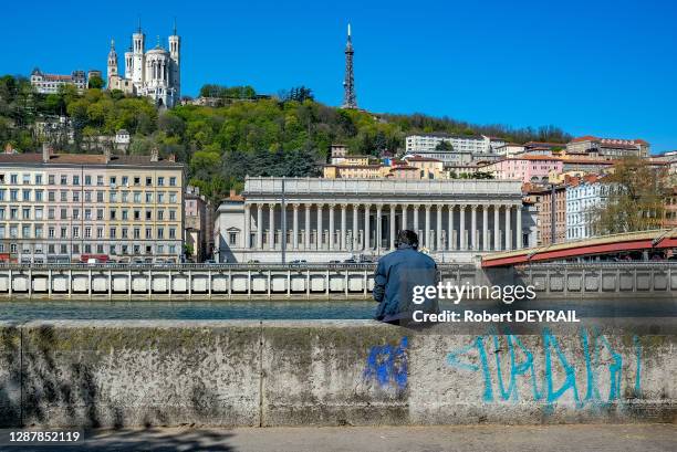 Un jeune homme seul écoute de la musique avec un casque assis en face de la Basilique de Fourvière lors du 20ème jour de confinement dû à la pandémie...