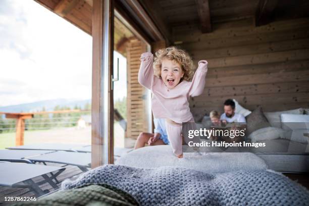 small girl with family playing in bedroom on holiday, jumping. - children jumping bed stock-fotos und bilder