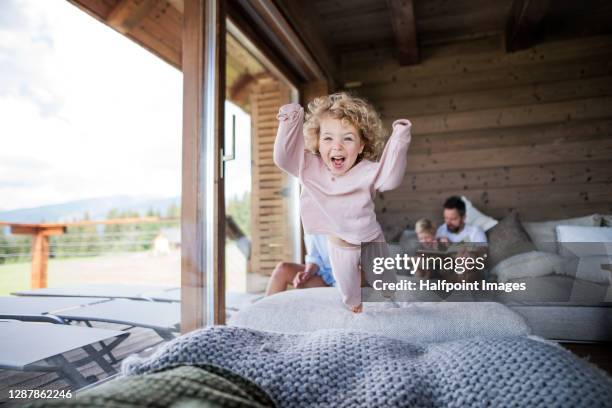 small girl with family playing in bedroom on holiday, jumping. - kids hotel bildbanksfoton och bilder