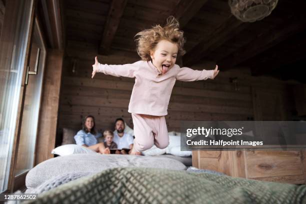 small girl with family playing in bedroom on holiday, jumping. - pajama stockfoto's en -beelden