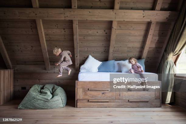 small children playing in bedroom on holiday, jumping from bed. - a boy jumping on a bed stock pictures, royalty-free photos & images