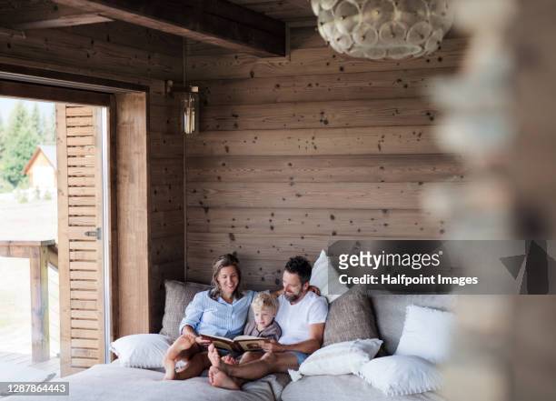 happy family with small child reading on bed on holiday. - cottage ストックフォトと画像