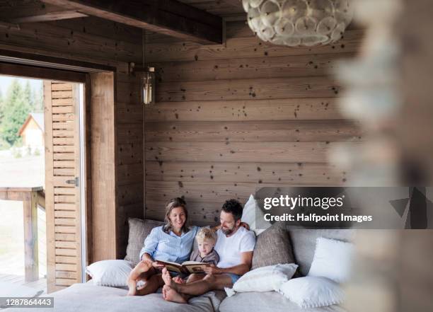 happy family with small child reading on bed on holiday. - cottage family stock pictures, royalty-free photos & images