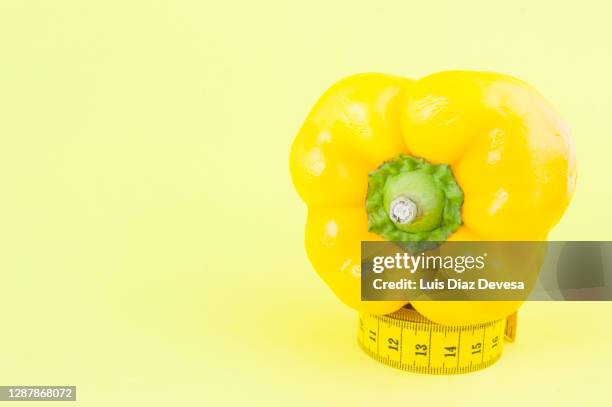 yellow bell pepper on yellow background above tape measure - gele paprika stockfoto's en -beelden