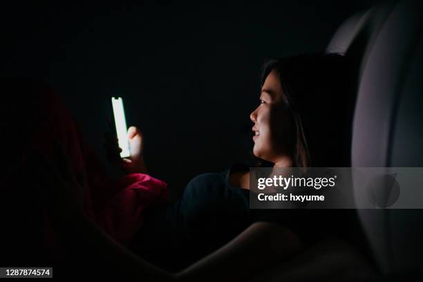 joven mujer asiática usando el teléfono inteligente en la oscuridad - ignorance fotografías e imágenes de stock