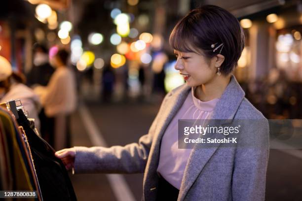 young woman shopping on street at night, looking for clothes - christmas decorations in store stock pictures, royalty-free photos & images