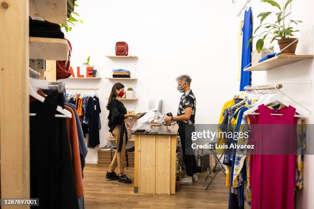 woman purchasing clothes at fashion store post pandemic - sales assistant furniture stock pictures, royalty-free photos & images