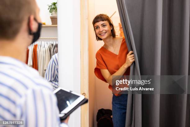 female customer trying on clothes in fashion store - anprobekabine stock-fotos und bilder