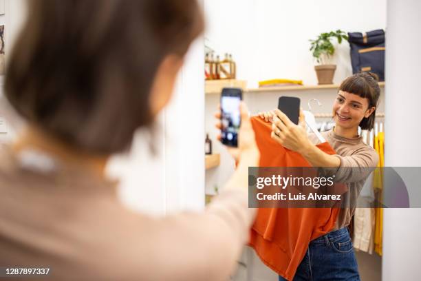 woman taking selfie with a top in garment store - mirror selfie stock pictures, royalty-free photos & images