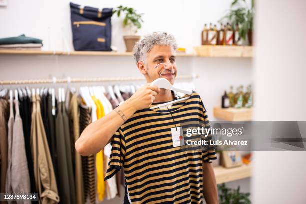 male customer buying clothes at garment store - mens clothing stock pictures, royalty-free photos & images