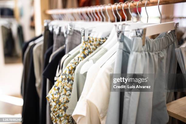 garments hanging on racks in fashion store - damkläder bildbanksfoton och bilder