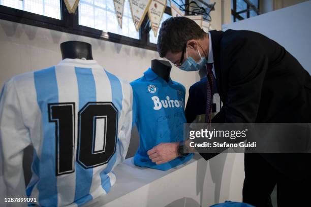 Man wearing protective prepares Diego Armando Maradona football shirts for auction during the preparation of the "Sport Memorabilia" auction on...