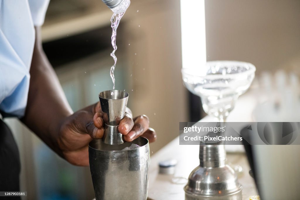 Barman pouring alcohol into cocktail shaker