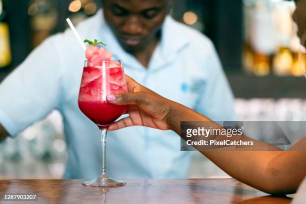 female drinking strawberry daiquiri at bar - daiquiri stock pictures, royalty-free photos & images