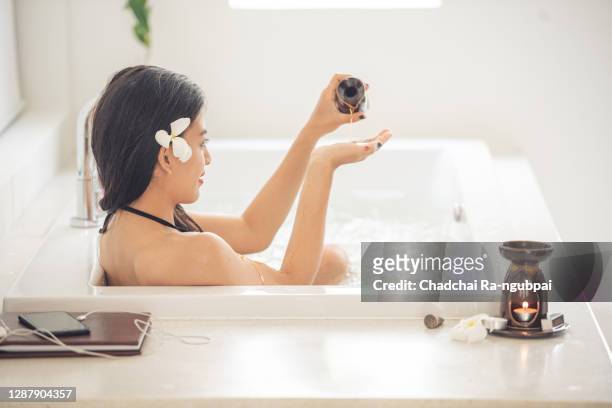 asian woman is using soap to bath in the bathtub at the bathroom. - japanese women bath stock pictures, royalty-free photos & images