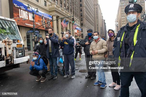 Small crowd wearing masks gather and takes to watch the Macy's Thanksgiving Day Parade on November 26, 2020 in New York City. The annual holiday...