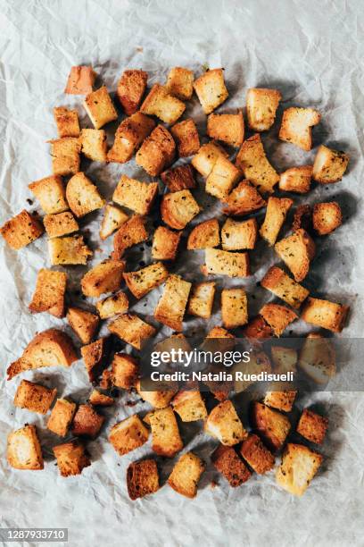 bread croutons cut in cubes on baking paper baked with oil and dry herbs. - krutong bildbanksfoton och bilder