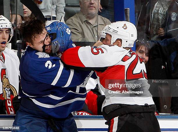 Luke Schenn of the Toronto Maple Leafs punches Chris Neil of the Ottawa Senators during NHL action at the Air Canada Centre October 8, 2011 in...