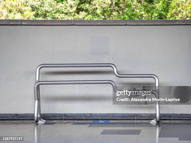 modern design stainless metal pipes bench in subway station by a white wall - incómodo fotografías e imágenes de stock
