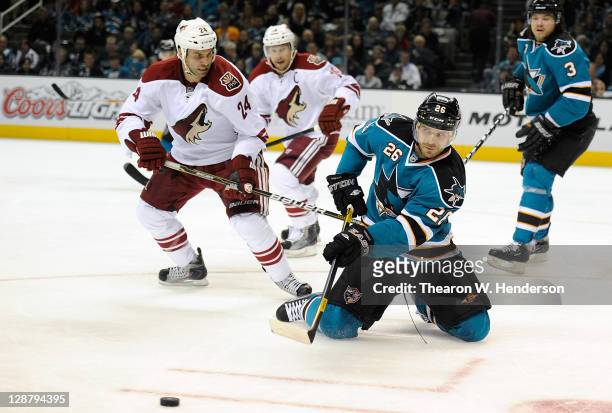 Michal Handzus of the San Jose Sharks passes the puck from his knees in front of Kyle Chipchura of the Phoenix Coyotes during an NHL hockey game at...
