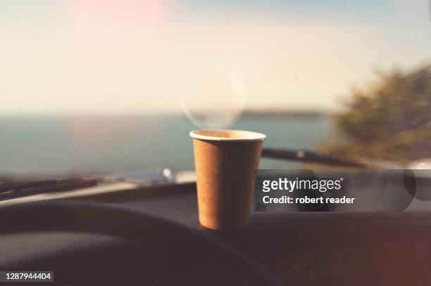 disposable paper coffee cup on dashboard - takeaway coffee stockfoto's en -beelden