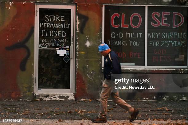 Person passes G&D Military Surplus, Inc. Army & Navy store on Waverly Avenue in Patchogue, New York on November 12, 2020 during the Coronavirus...