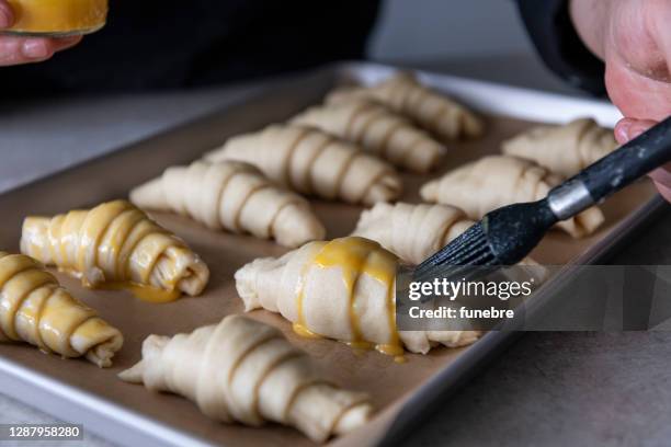 baker putting yolk on croissants - croissant stock pictures, royalty-free photos & images