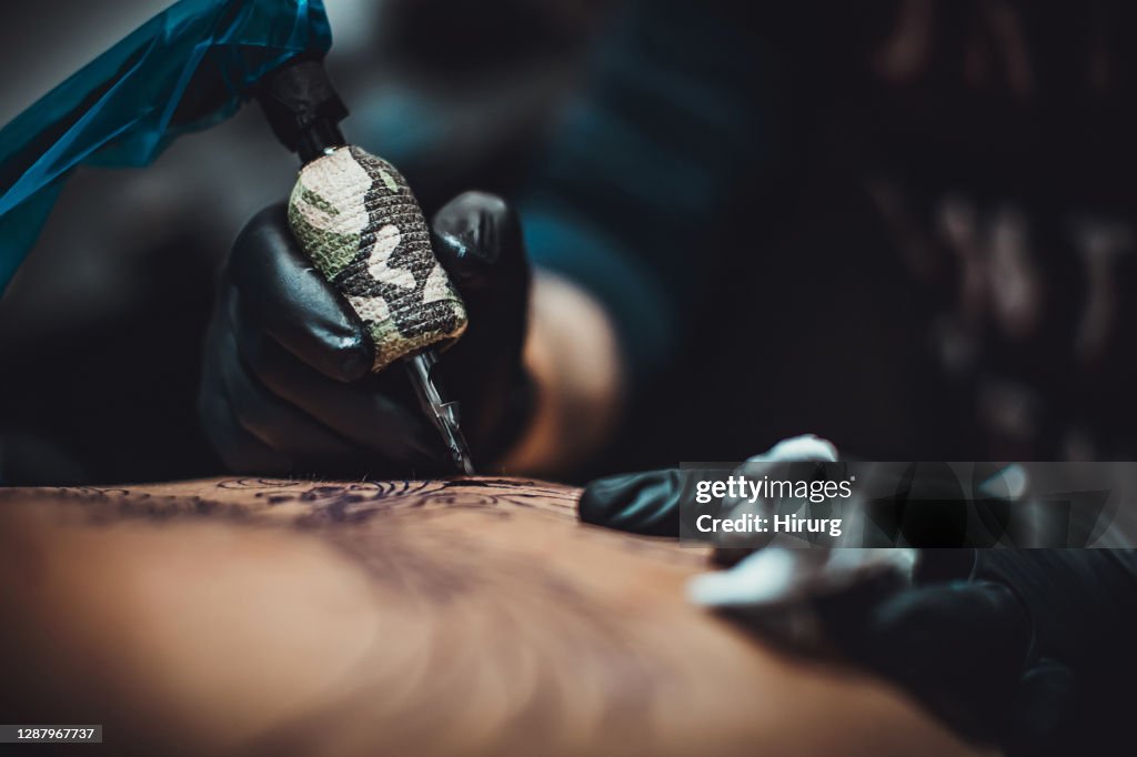 Un artista tatuando la espalda de un hombre en el estudio