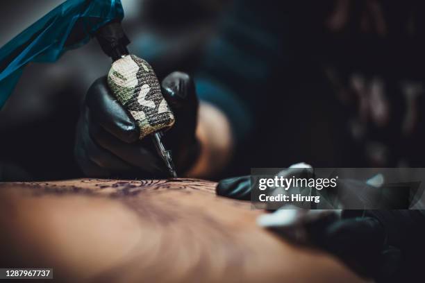 one artist tattooing a man's back in studio - tattooing stock pictures, royalty-free photos & images