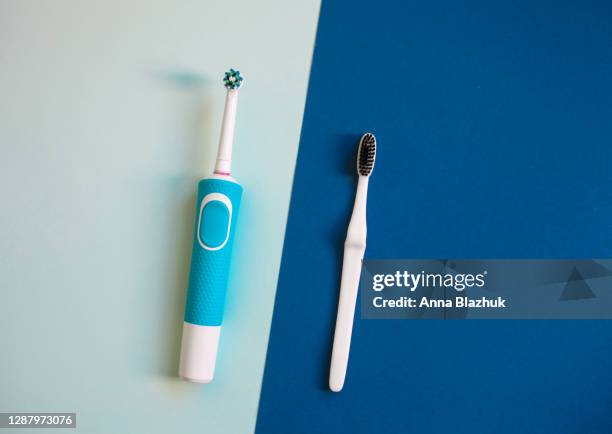 comparison of manual toothbrush vs electric toothbrush over colorful blue background. - pasta de dentes imagens e fotografias de stock