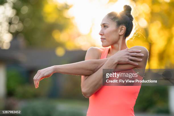 hermosa atleta femenina que se estira antes del entrenamiento al aire libre - estirar fotografías e imágenes de stock