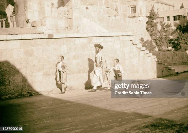 Orthodox Jew with 2 youngsters, on Sabbath journey to Wailing Wall. 1934, Jerusalem, Israel.