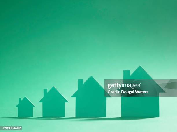 four green cardboard cutout houses on green background of increasing size. - mutuo casa foto e immagini stock