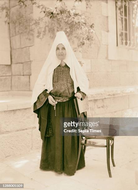 Ruth the Moabitess, a woman wearing traditional Palestinian clothing including a dress with an embroidered chest panel and headscarf. 1925.