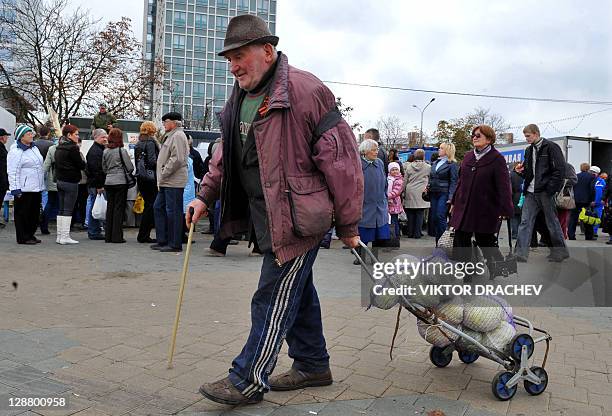 An elderly man pulls a cart with his purchase, heads of cabbage, an outdoor market in Minsk, on October 9, 2011. For several months now Belarus...