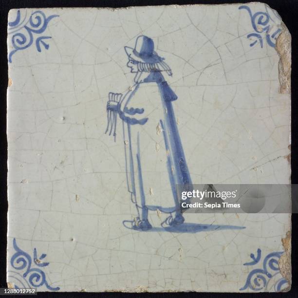 Occupation tile, blue with standing nobleman with handkerchief In his hand, long cloak, top hat, corner pattern ox head, wall tile tile sculpture...