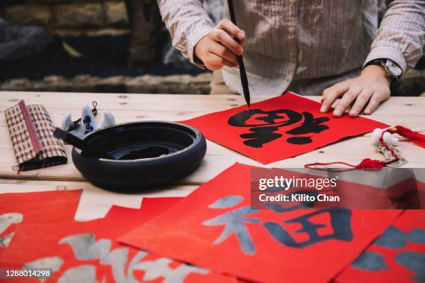 asian woman writing the chinese character "fu" (福), meaning good luck and fortune for the new year - caligrafia imagens e fotografias de stock