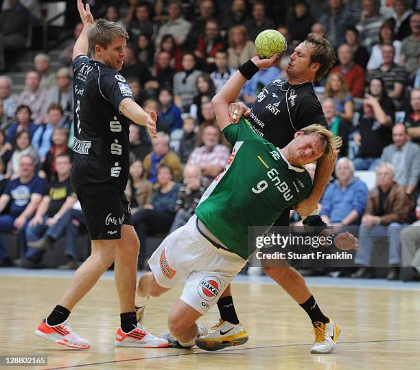 Manuel Spaeth of Goeppingen is challenged by Morten Slundt and Bostjan Hribar of Hildesheim during the Toyota Handball Bundesliga match between...