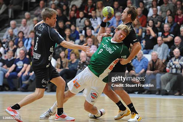 Manuel Spaeth of Goeppingen is challenged by Morten Slundt and Bostjan Hribar of Hildesheim during the Toyota Handball Bundesliga match between...