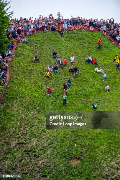 Participants chase a wheel of cheese during the annual cheese rolling event on Cooper's Hill in Brockworth in Gloucestershire.