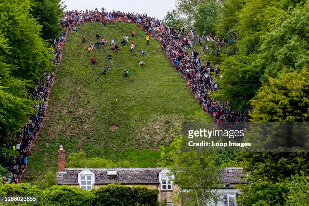 Participants chase a wheel of cheese during the annual cheese rolling event on Cooper's Hill in Brockworth in Gloucestershire.