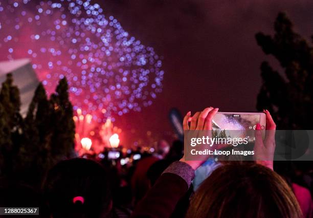 Woman photographing fireworks using smartphone during Chinese New Year celebrations in Kowloon in Hong Kong.