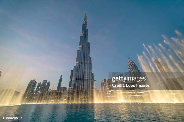 The Dubai Fountain dances in golden light under the Burj Khalifa.