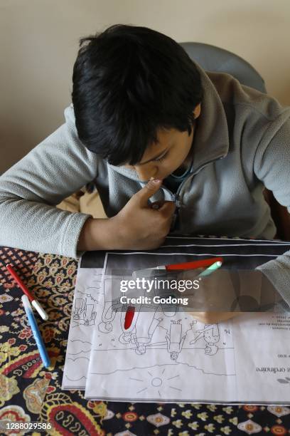 Boy coloring a christian picture in Eure, France.