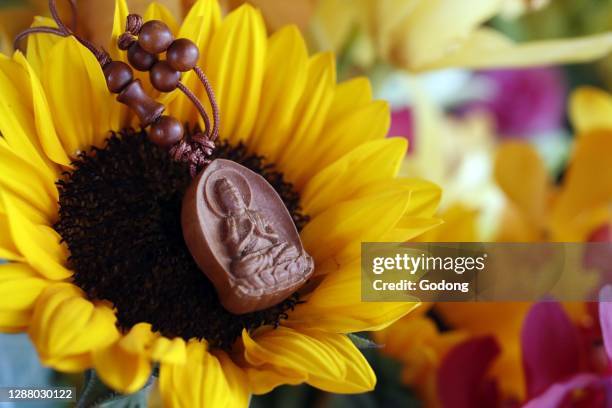 Wood buddha pendant on flower. Ho Chi Minh City. Vietnam.