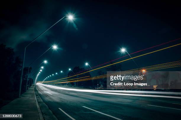Long exposure light streaks of car lights on an urban bridge at night.