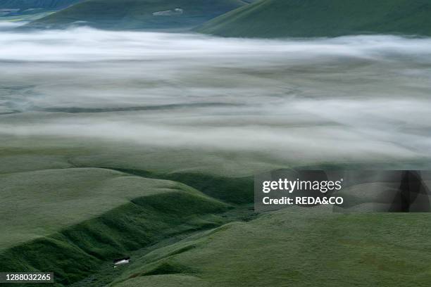 Fog on the Pian Grande of Castelluccio di Norcia. Fosso dei Mergani sinkhole. Umbria. Italy. Europe.