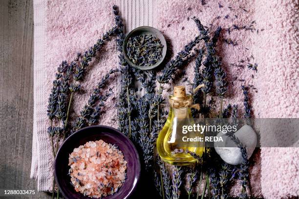 Concept. Flat lay of fresh and dry lavender flowers. Essential oil. Pink salt. Stones as heart shape. Aromatic candle on pink bath towel over...