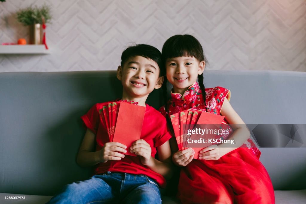 Lovely Asian sibling holding red envelopes with traditional dressing up celebrate Chinese new year.