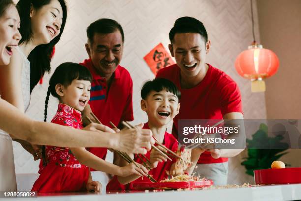 happy asian chinese family tossing yee sang or yu sheng during chinese new year dinne - chinese new year food stock pictures, royalty-free photos & images